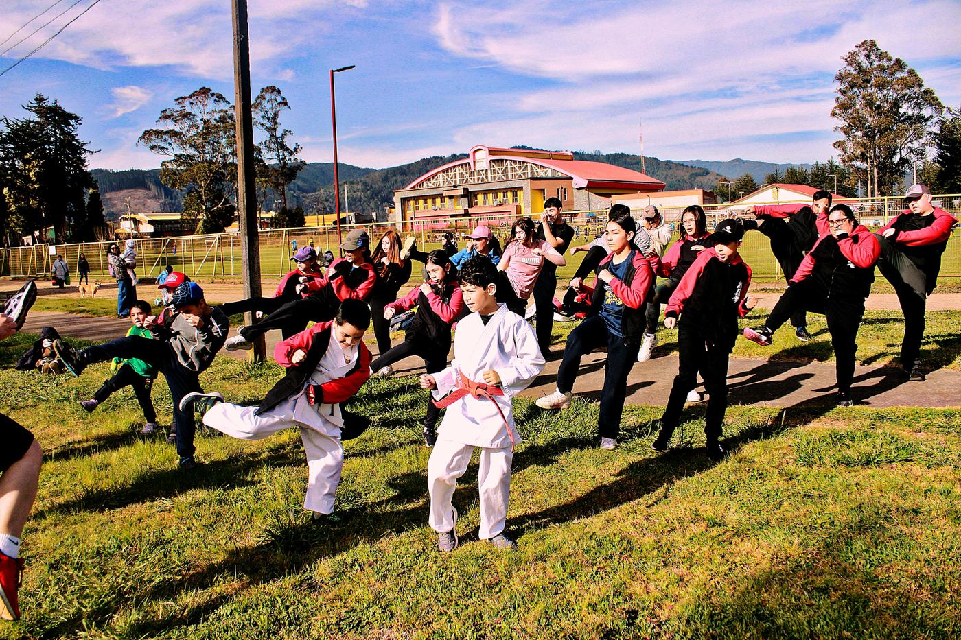 Entrenamiento grupal con patadas al aire libre, con las montañas al fondo